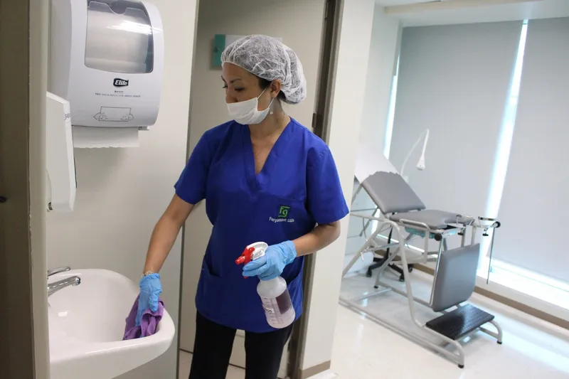 Operaria desinfectando una camilla en un box clínico