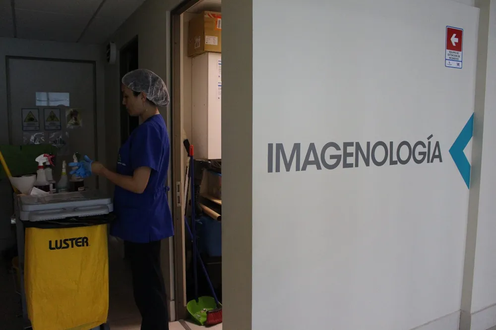 Operaria de Fergomant con carro de aseo junto a la sala de imagenología de una clínica